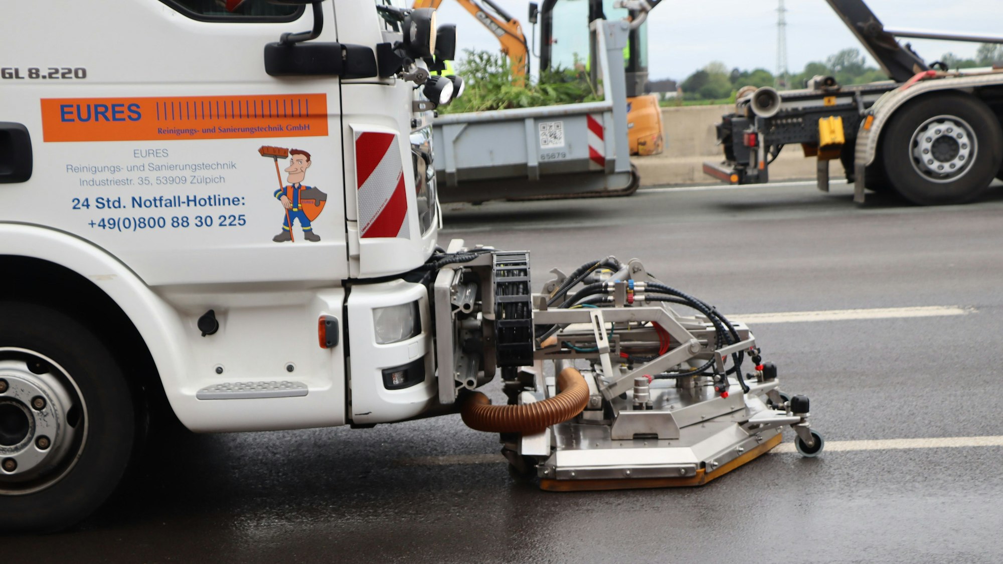 Mit Spezialgeräten wird der Ölfilm von der Fahrbahn geholt. Die Beete hinter der Leitplanke auf der rechten Fahrbahnseite mussten ebenfalls über eine Länge von etwa 250 Metern ausgegraben werden.
