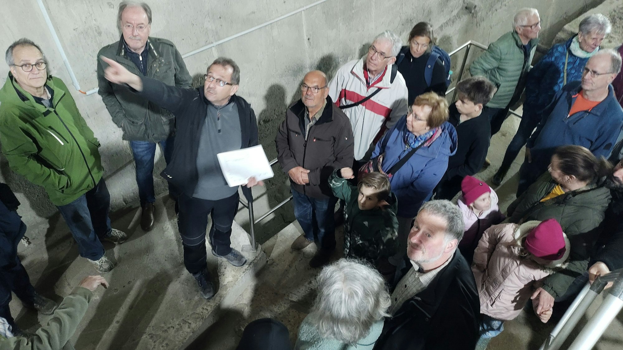 Mehrere Besucher stehen um Wolfgang Hörnchen, der in die Höhe zeigt und etwas erläutert.