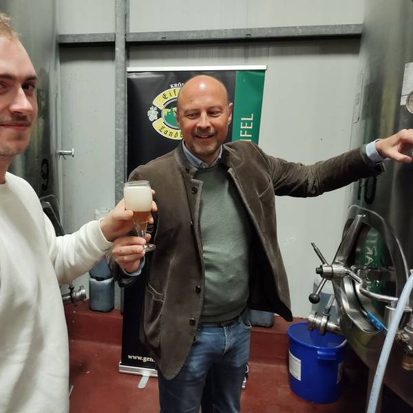 Johannes Schweizer reicht einem Besucher ein gezapftes Bier.