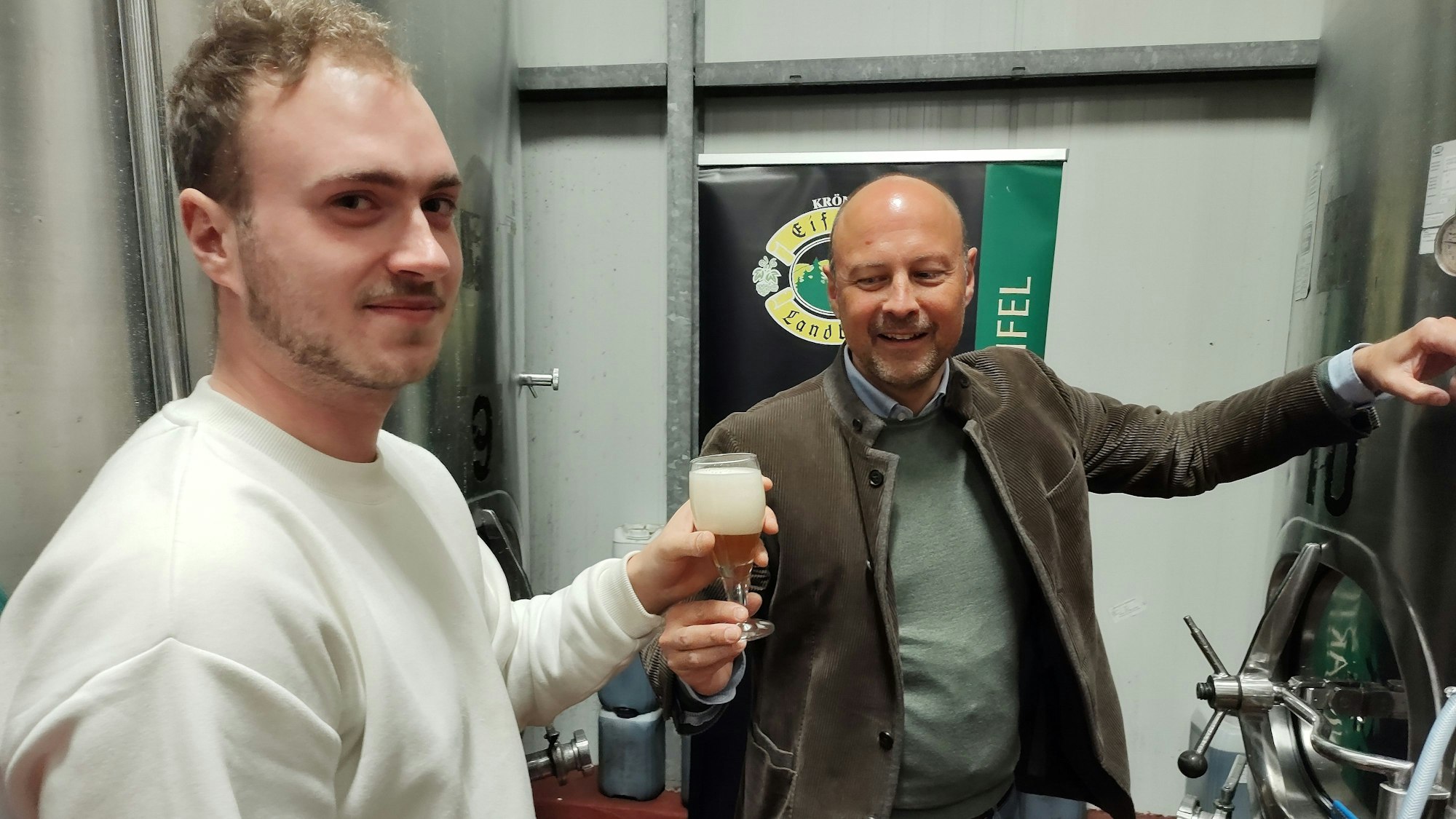 Johannes Schweizer reicht einem Besucher ein gezapftes Bier.