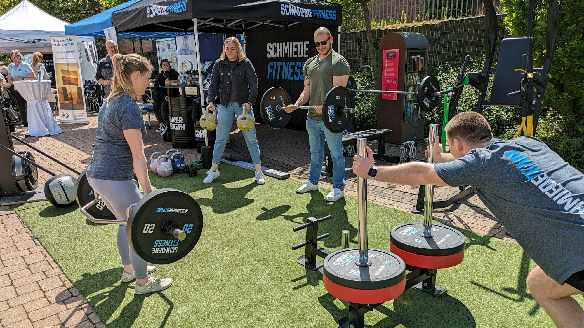 Menschen probieren unter freiem Himmel Sportgeräte aus.