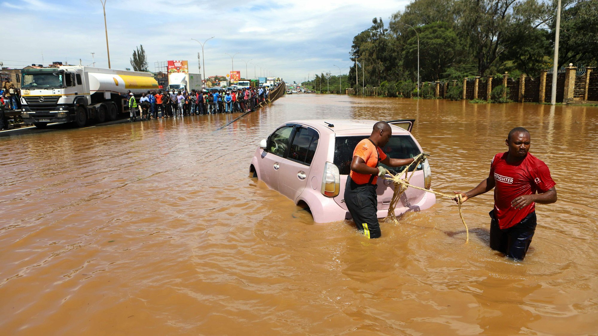 Das von der chinesischen Staatsagentur Xinhua verbreitete Bild zeigt Menschen, die im Hochwasser ein Auto ziehen.