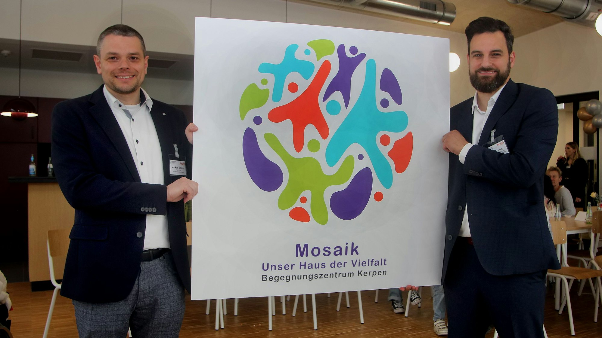 Beigeordneter Markus Meurer (l.) und Dezernent Cem Yilmaz präsentieren das von Kerpener Schülerinnen und Schülern entwickelte Mosaik-Logo.