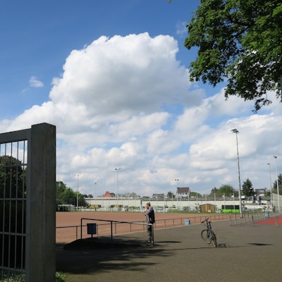 Zu sehen ist der Eingangsbereich der Sportanlage, die die Brachfläche umgibt. Hier trainiert und spielt unter anderem die Germania Ossendorf. Foto von Hans-Willi Hermans