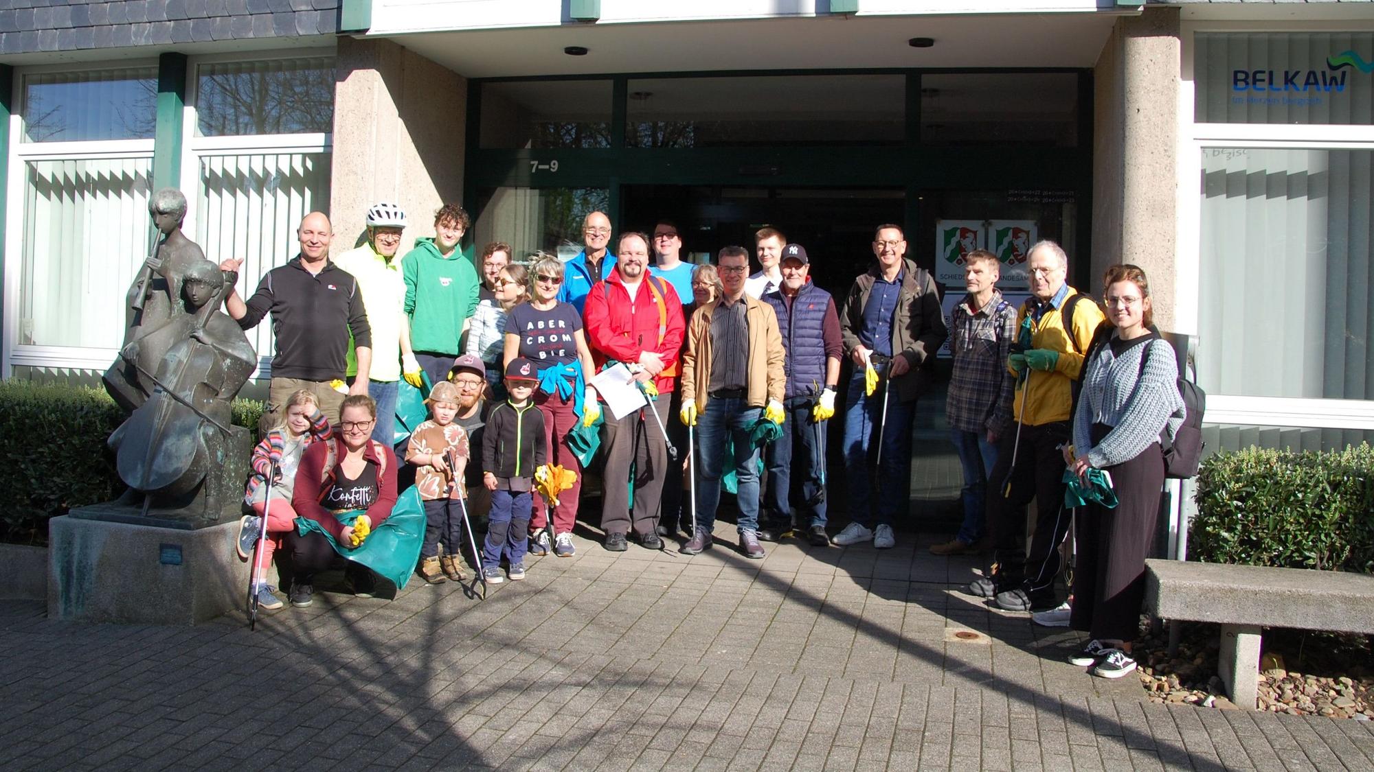 Eine Gruppe Erwachsene und Kinder mit Müllzangen vor dem Burscheider Rathaus