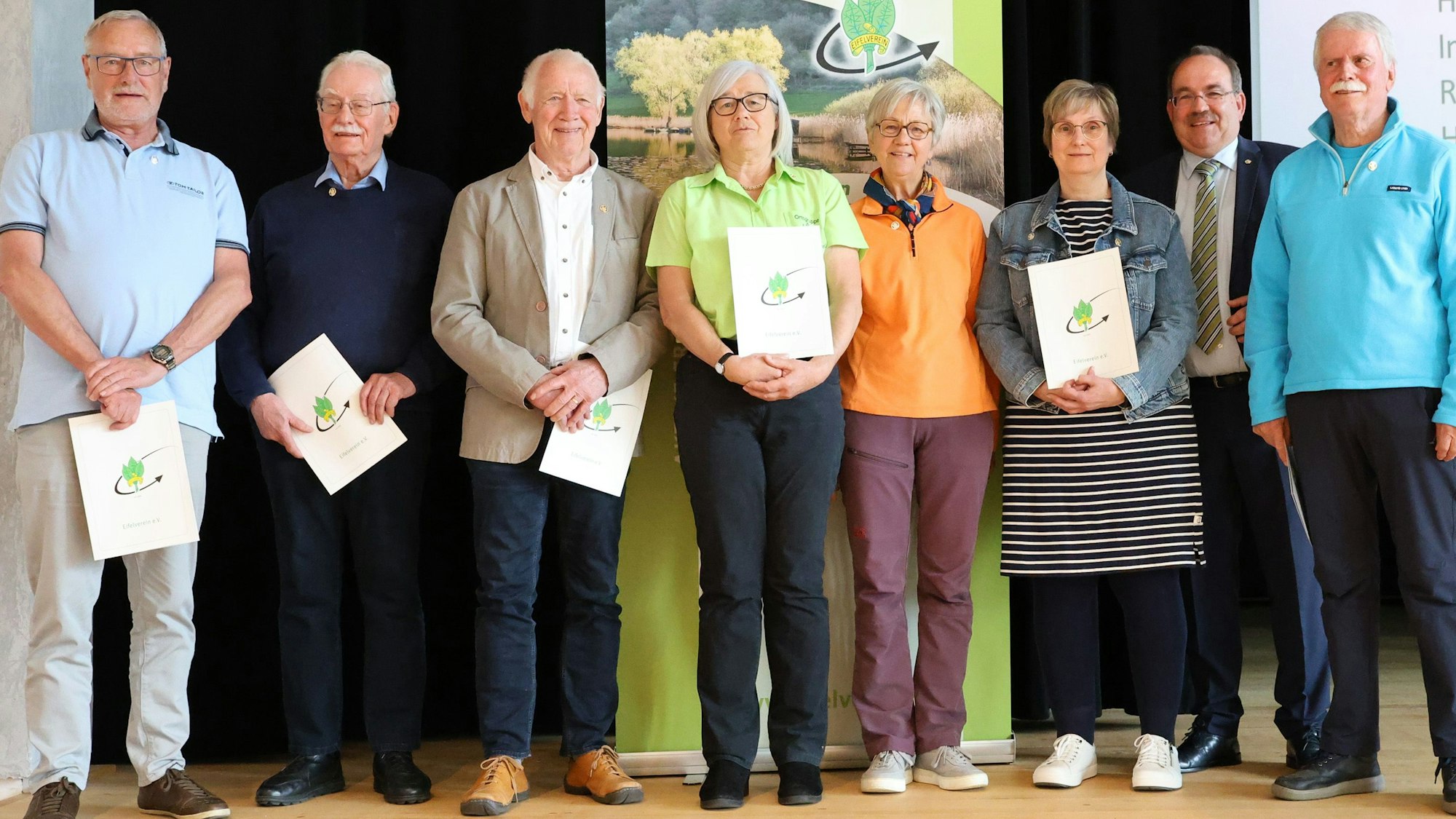 Fünf Männer und drei Frauen stehen in Gemünd auf der Bühne des Kursaals. Einige halten Urkunden mit dem Logo des Eifelvereins in den Händen.