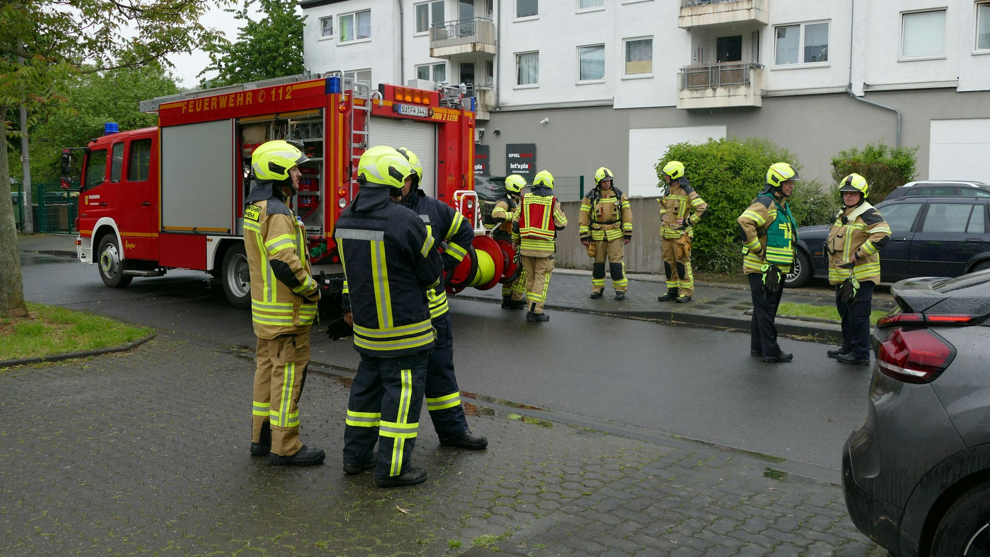 Feuerwehrleute stehen vor dem Wohnkomplex.