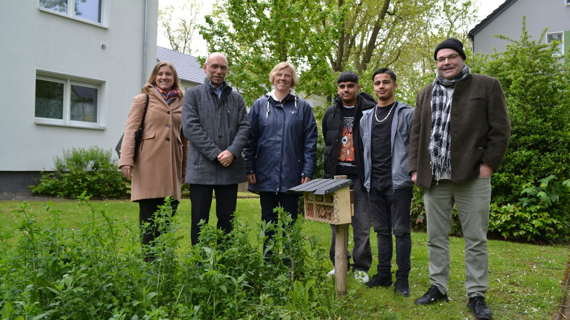 Vertreterinnen und Vertreter der Gewog, der Kalker Hauptschule und des Vereins EIgenart an einem neu aufgestellten Insektenhotel in Ensen.