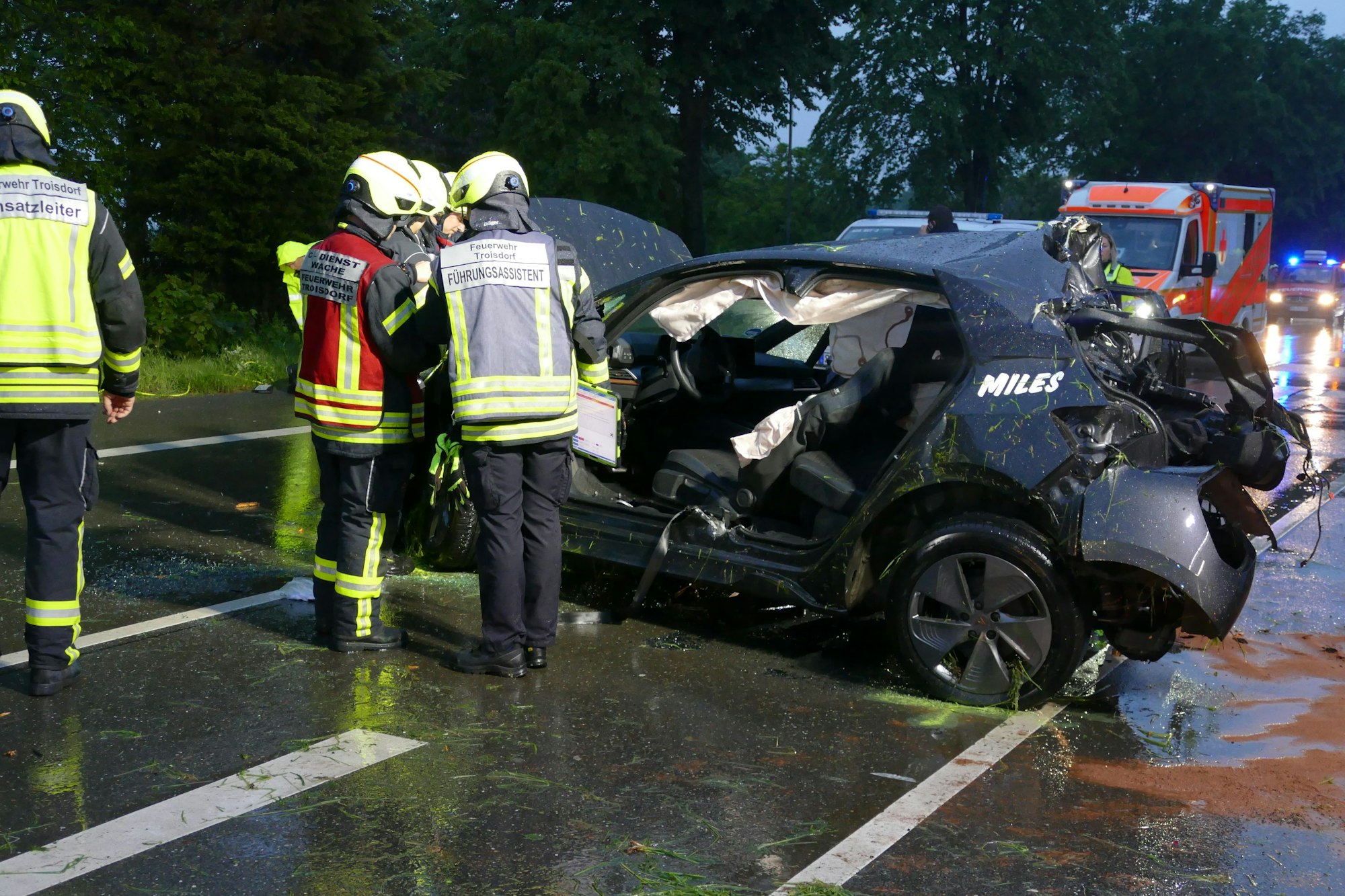 Feuerwehrleute neben einem Auto ohne Türen.