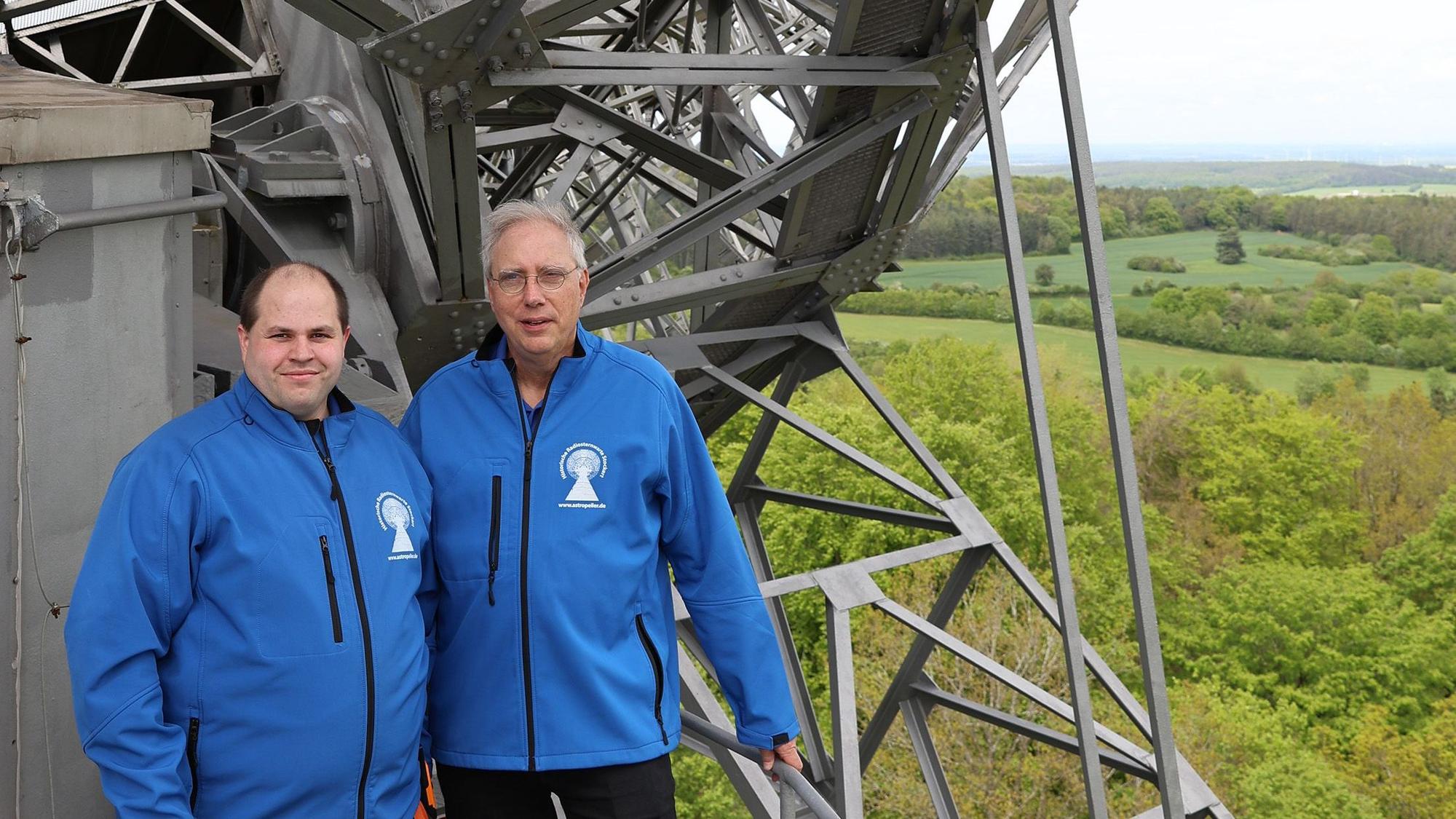Kevin Schmitz (l.) und Walter Grode stehen auf der Arbeitsplattform der Radioteleskopschüssel, rechts ist der Blick in die Weite der Eifellandschaft zu sehen.