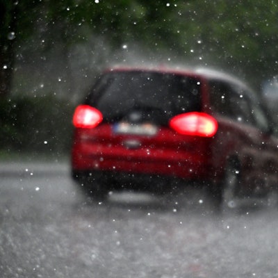 Ein Auto fährt durch einen Hagelschauer. Der DWD warnt vor Starkregen in Köln und der Region. (Symbolbild)