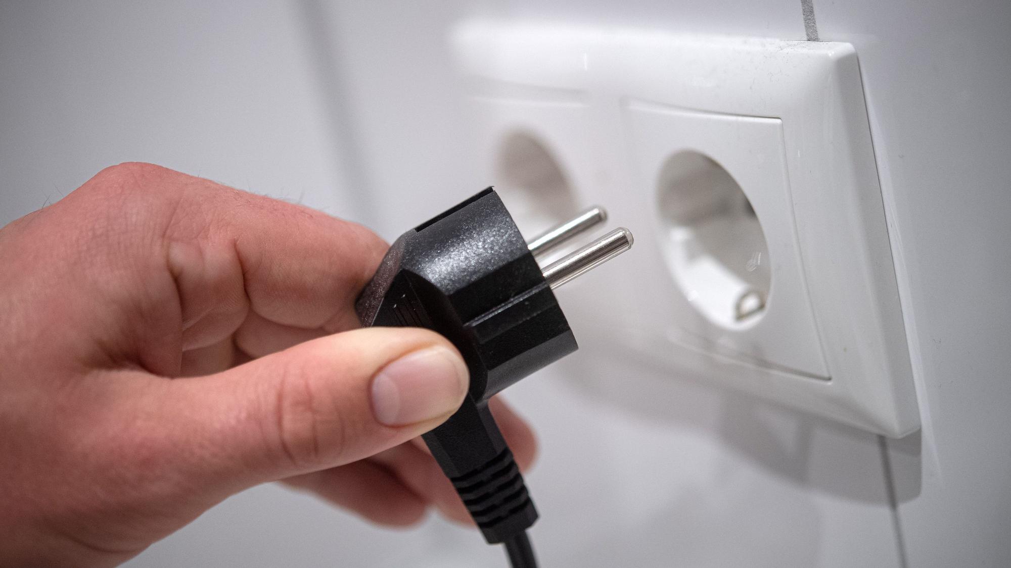 Ein Stecker wird in eine Steckdose gesteckt.