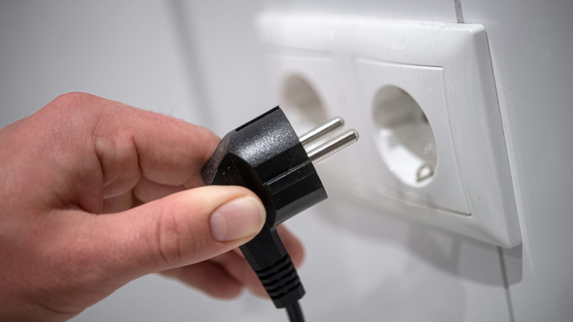 Ein Stecker wird in eine Steckdose gesteckt.