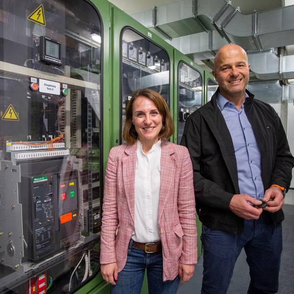 Eine Frau und ein Mann stehen vor einem Schaltschrank.