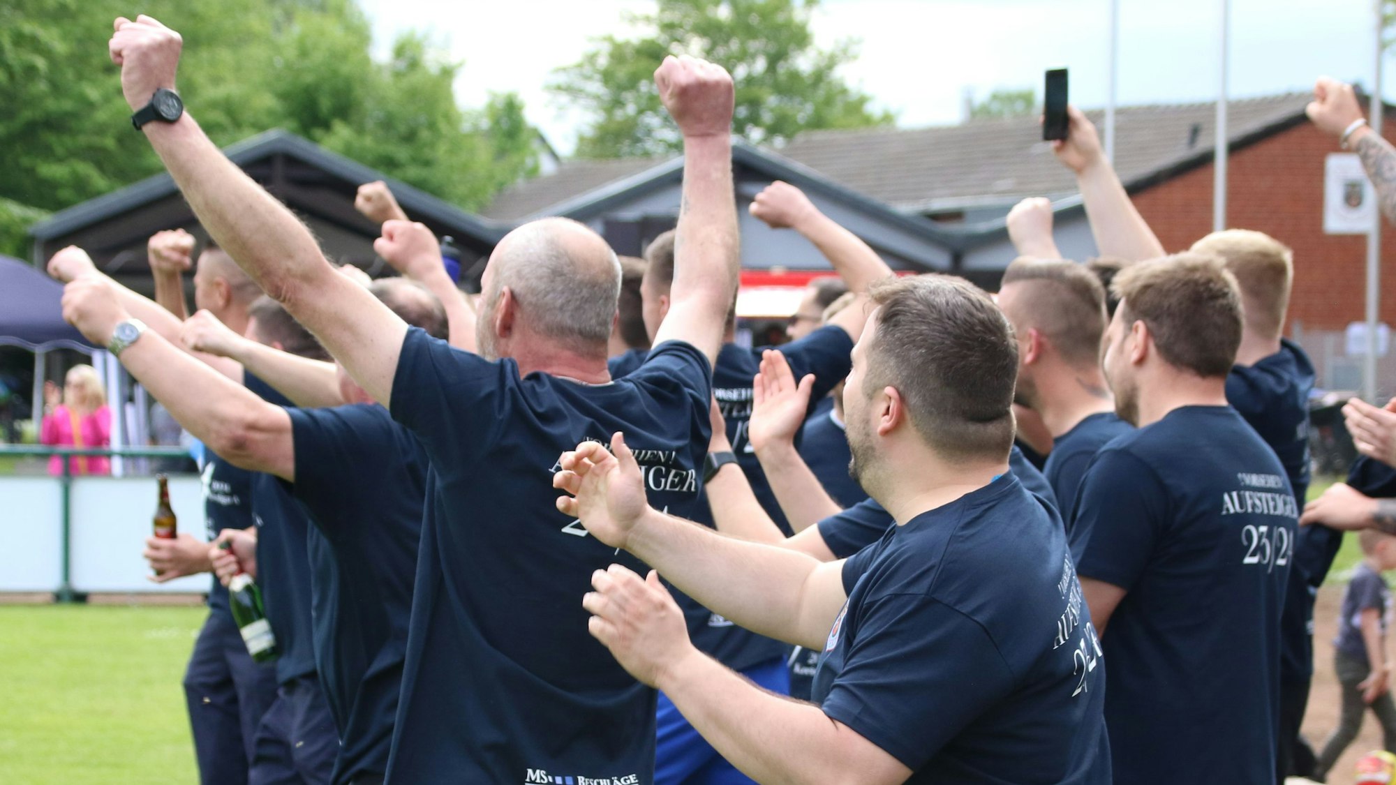 Fußballfans jubeln am Spielfeldrand.