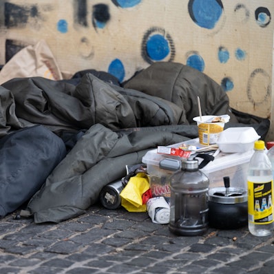 Eine Person liegt in der Innenstadt unter einem Schlafsack.