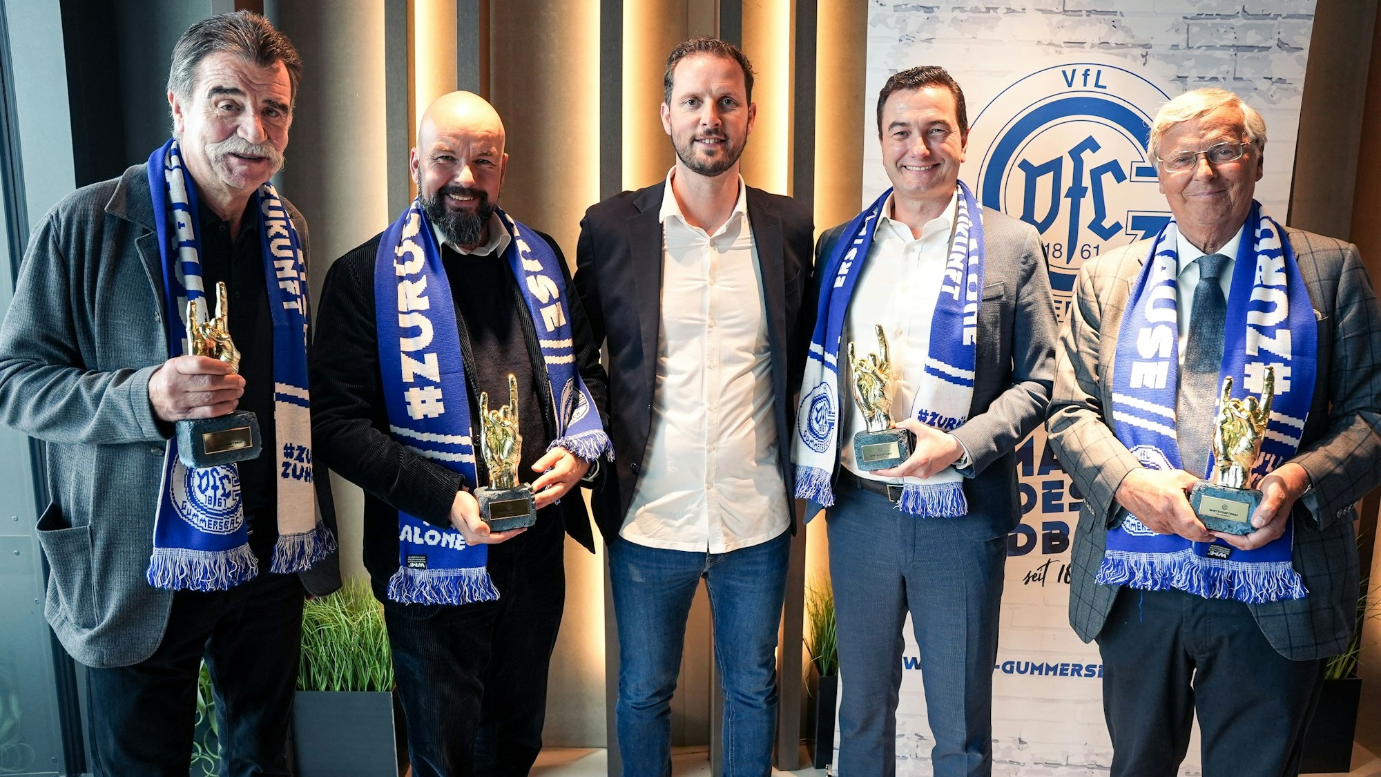 Gruppenbild: Heiner Brand, Thilo Schmid, Christoph Schindler, Dr. Thomas Wilk, und Wolfgang Bosbach stehen nebeneinander. Sie tragen Schals des VfL Gummersbach.