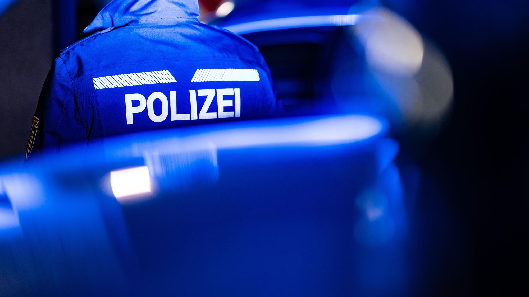 Ein Polizist steht neben einem Polizeiauto. (Symbolfoto)
