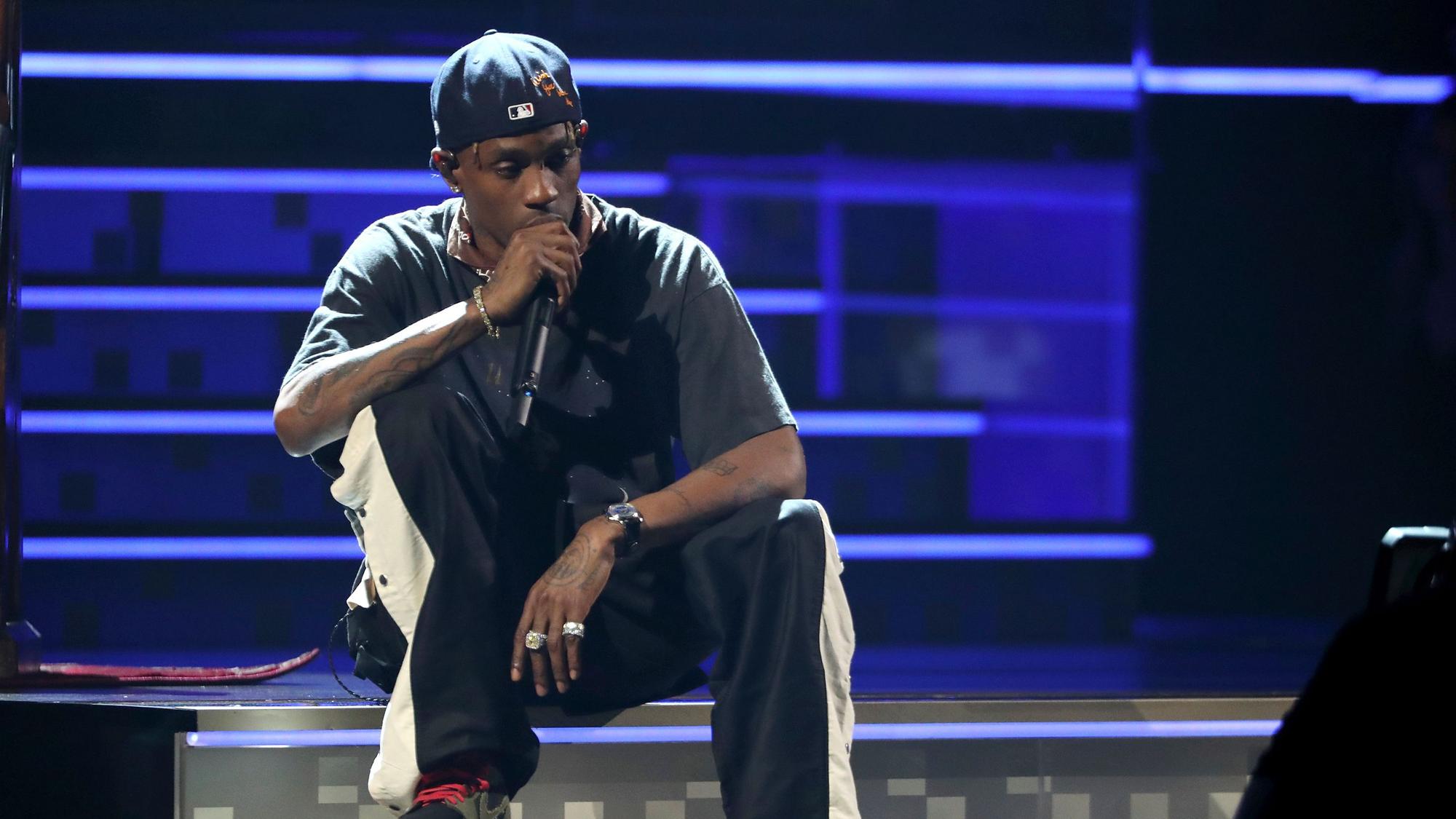 Travis Scott sitzt auf der Bühne.