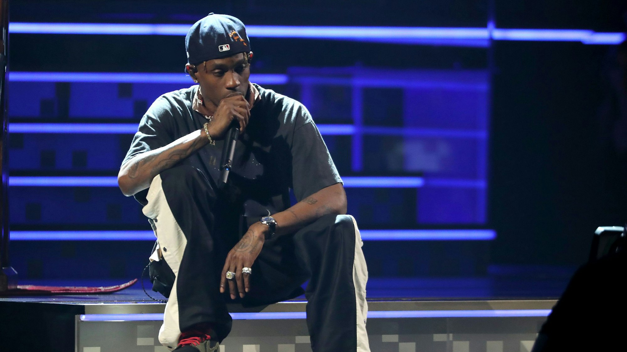Travis Scott sitzt auf der Bühne.