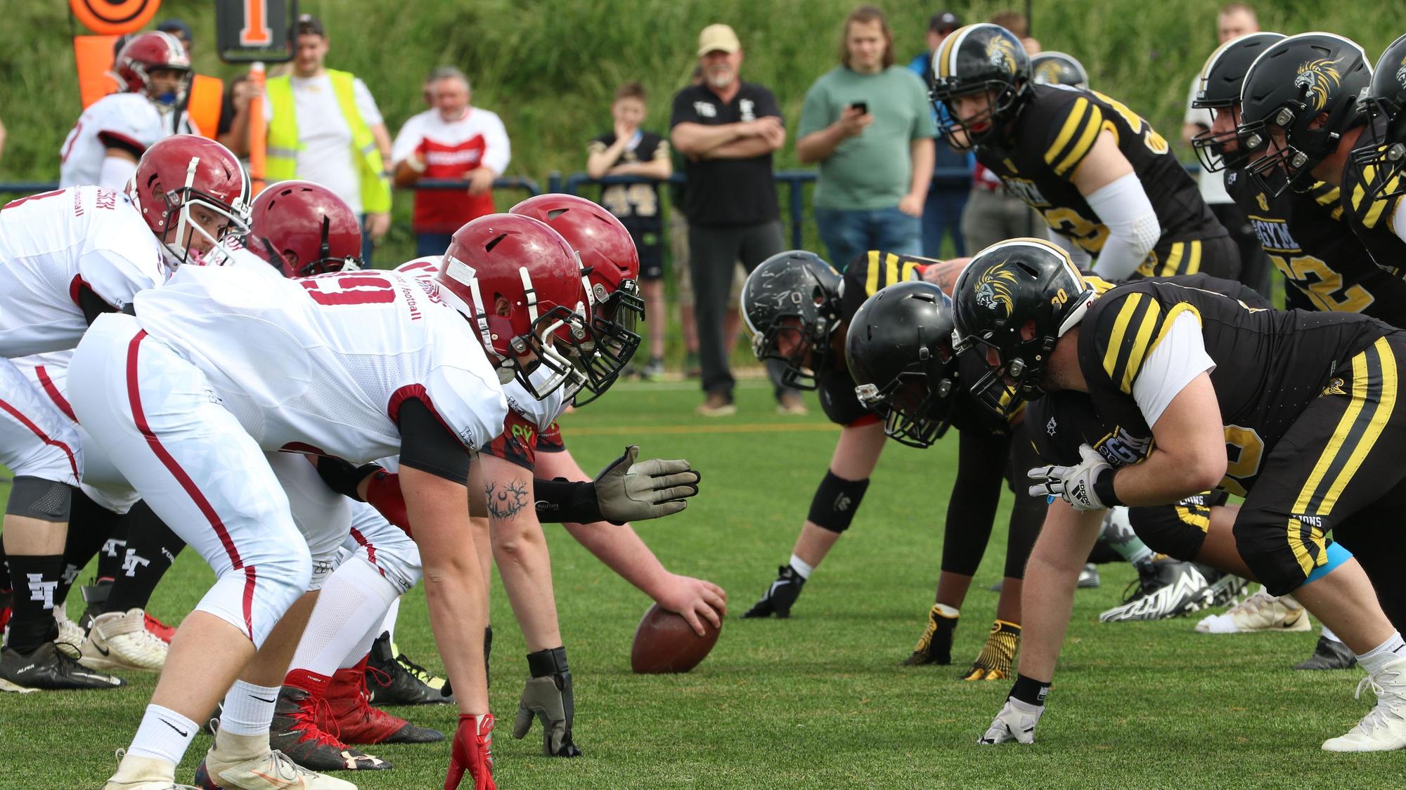 Saisonauftakt für die American Football Landesliga: Die Euskirchen Lions treten auf dem Rasen-Feld in schwarzen Trikots gegen die Iserlohn Titans in weißen Trikots an.