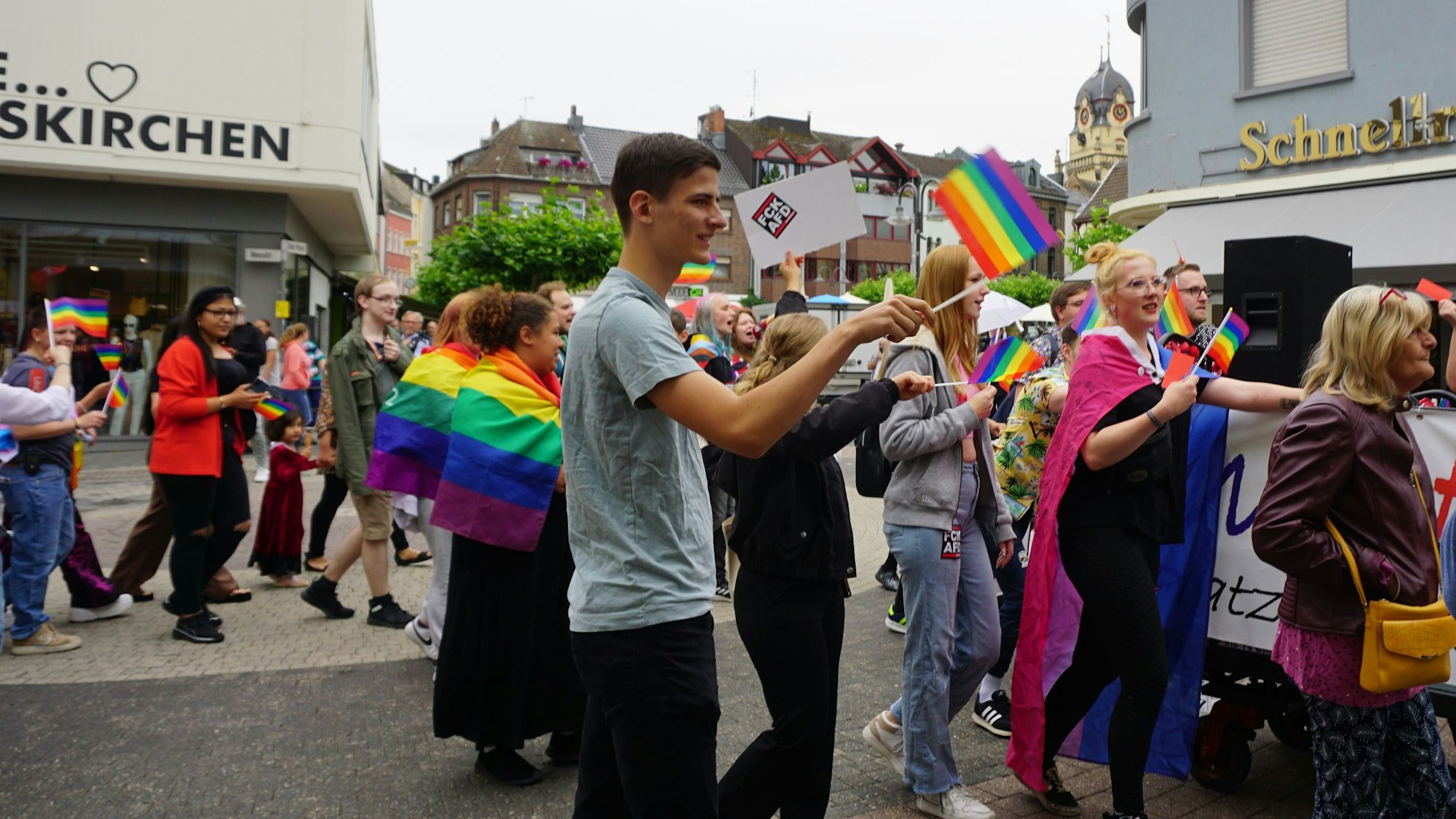 Einige Demonstranten laufen durch die Fußgängerzone von Euskirchen. Sie schwingen Regenbogenflaggen.