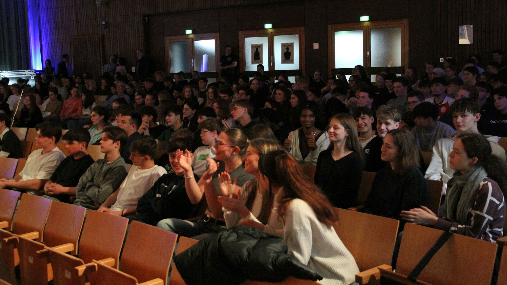 Schülerinnen und Schüler sitzen in einer Aula
