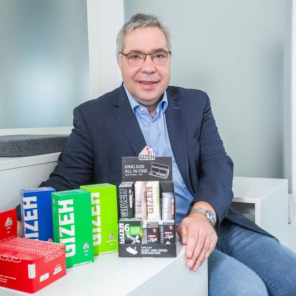 Ein Mann sitzt vor einer Reihe von bunten Schachteln.