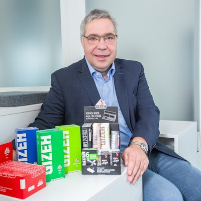 Ein Mann sitzt vor einer Reihe von bunten Schachteln.