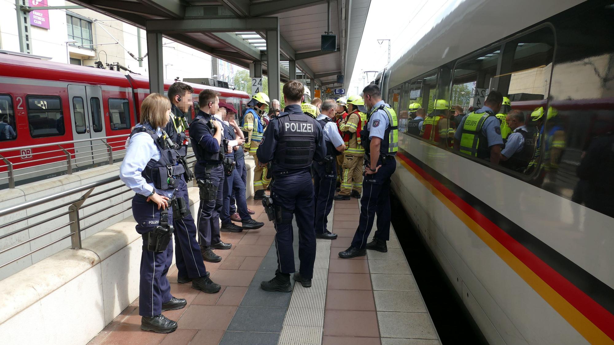 Bundespolizisten und Feuerwehrleute stehen neben dem betroffenen ICE.