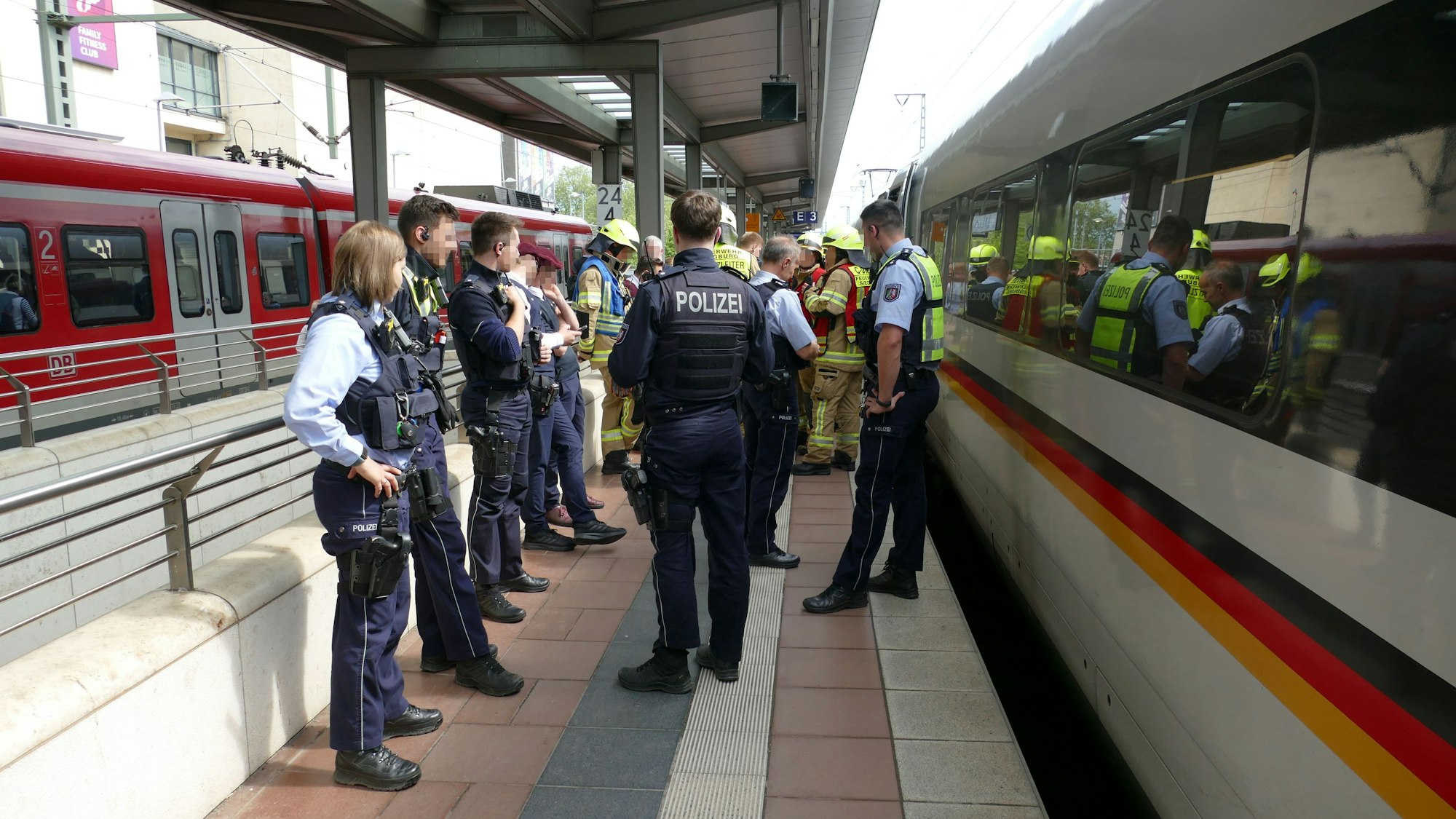 Bundespolizisten und Feuerwehrleute stehen neben dem betroffenen ICE.