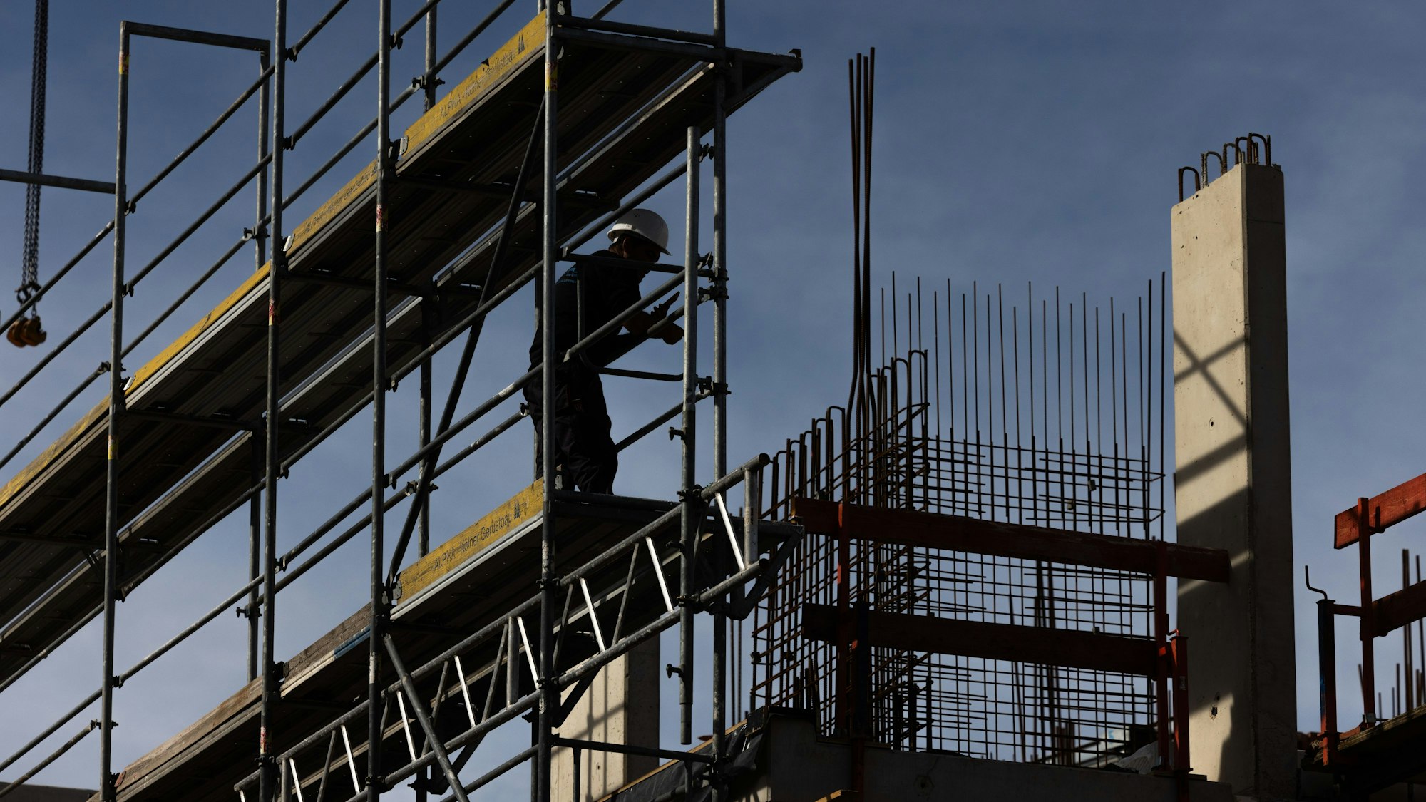 Ein Bauarbeiter steht auf einem Baugerüst.