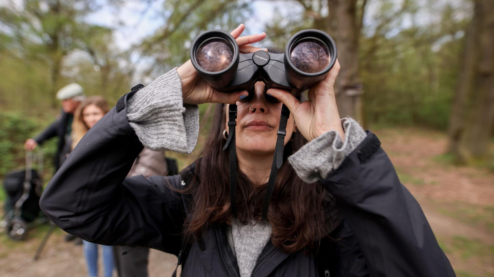 Im Vordergrund ist Jana Romero mit Fernglas zu sehen, verschwommen dahinter Michelle Etienne und Volker Brinkmann.