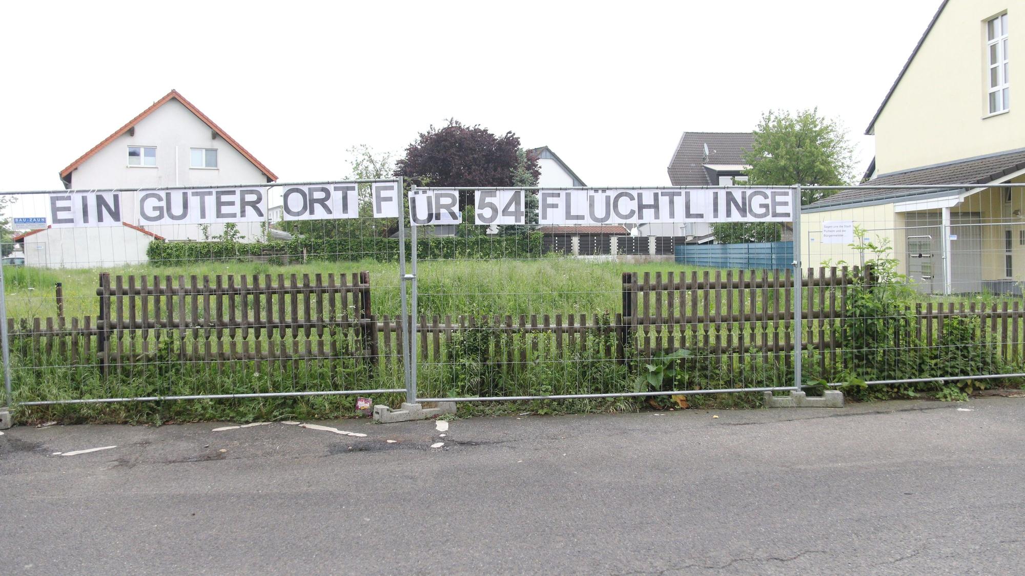 Ein Zaun, an dem der Schriftzug „Ein guter Ort für 54 Flüchtlinge“ hängt.