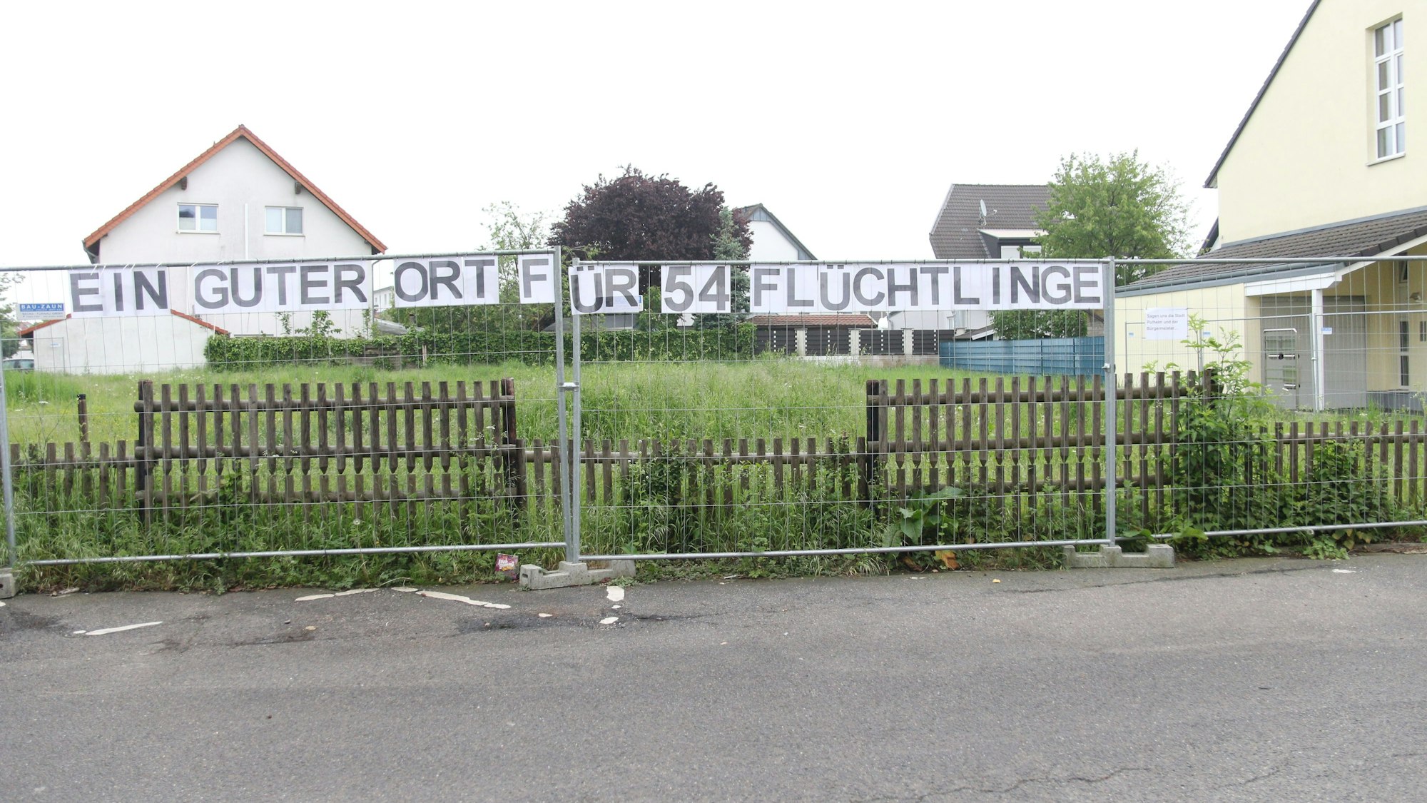 Ein Zaun, an dem der Schriftzug „Ein guter Ort für 54 Flüchtlinge“ hängt.