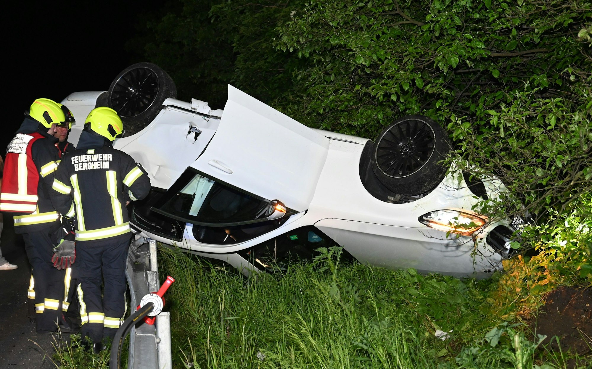 Auf dem Foto sind Feuerwehrleute an dem Unfallwagen zu sehen, der auf dem Dach liegt.