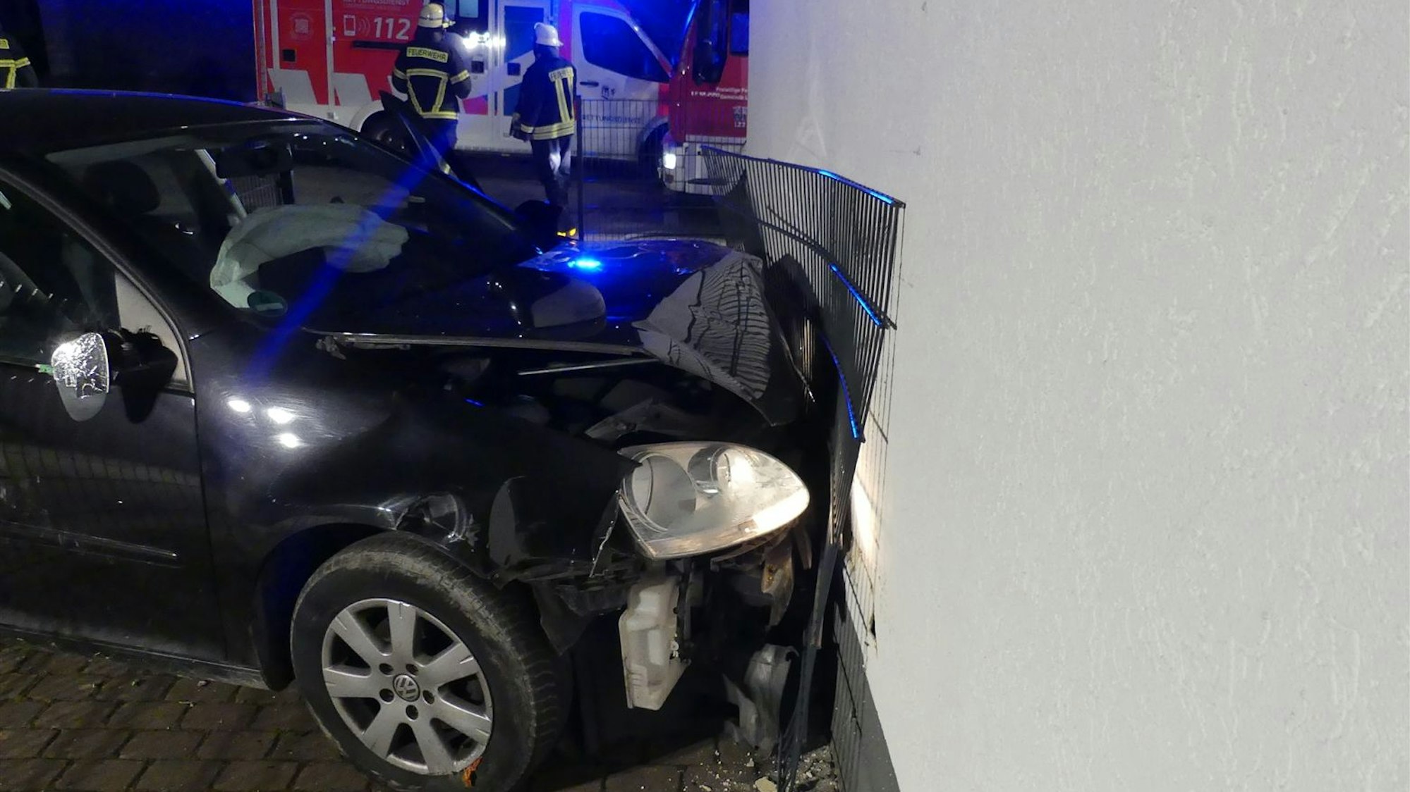 Das Auto mit eingedrückter Front an der Mauer.