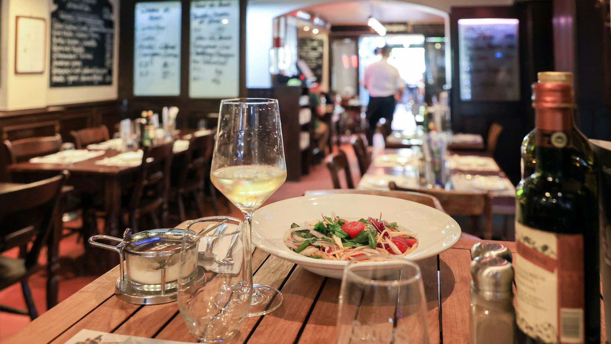 Innenraum mit Holztischen, Tafeln und italienischem Essen.
