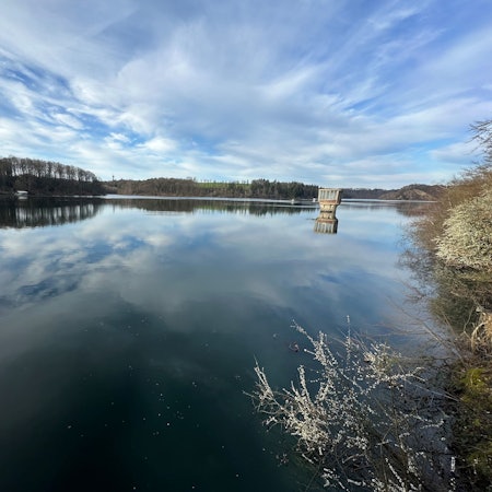 Wolken spielen sich im Wasser einer Talsperre