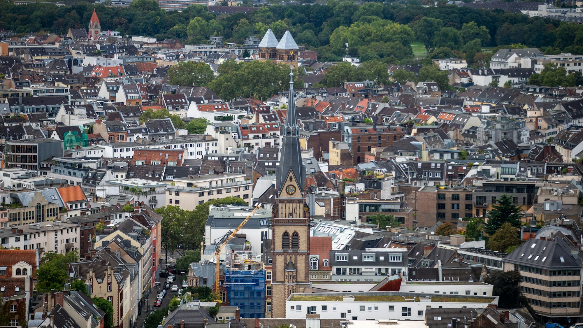 Blick über Köln mit vielen Mehrfamilienhäusern und einer Kirche.