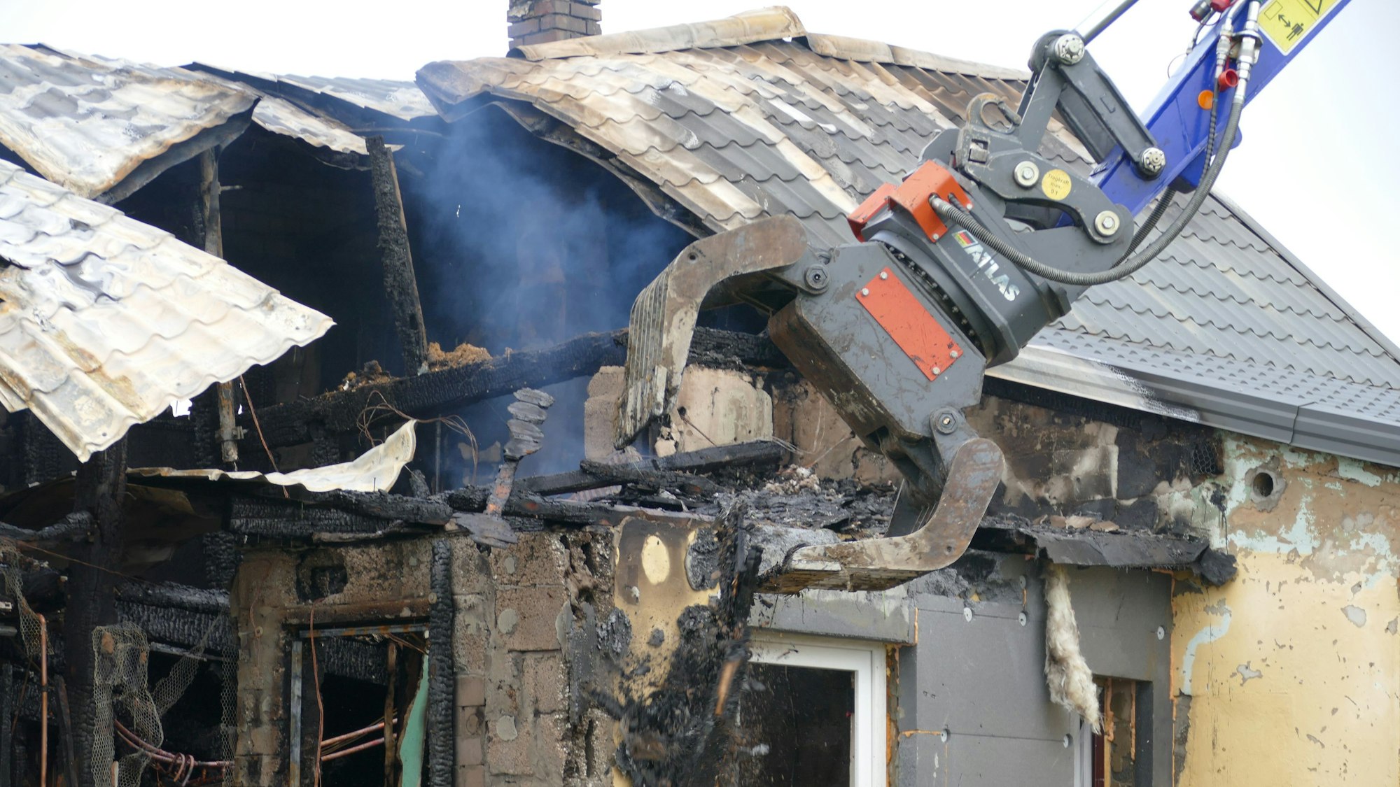 Ein Bagger reißt einen Teil des Hauses ein.