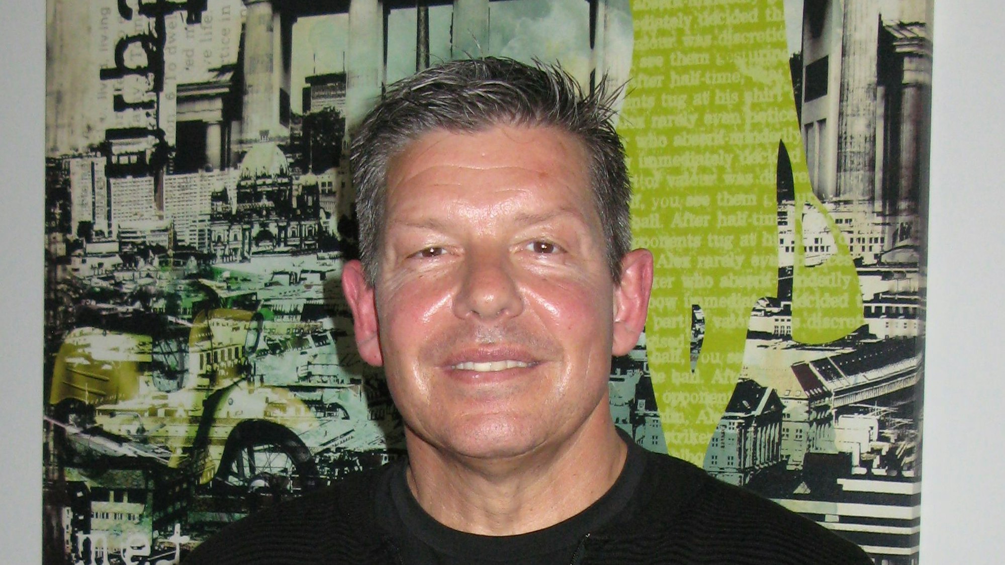 Ein Mann steht vor einem Plakat.