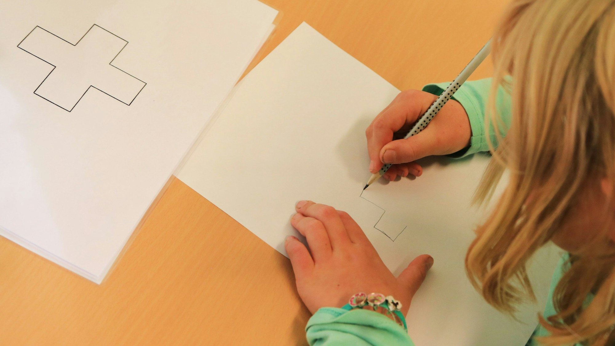 Ein Kind zeichnet etwas auf ein Blatt.