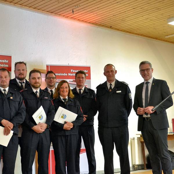 Zahlreiche Feuerwehrleute aus Nettersheim halten Urkunden mit dem Gemeindewappen in den Händen. Rechts steht Bürgermeister Norbert Crump.