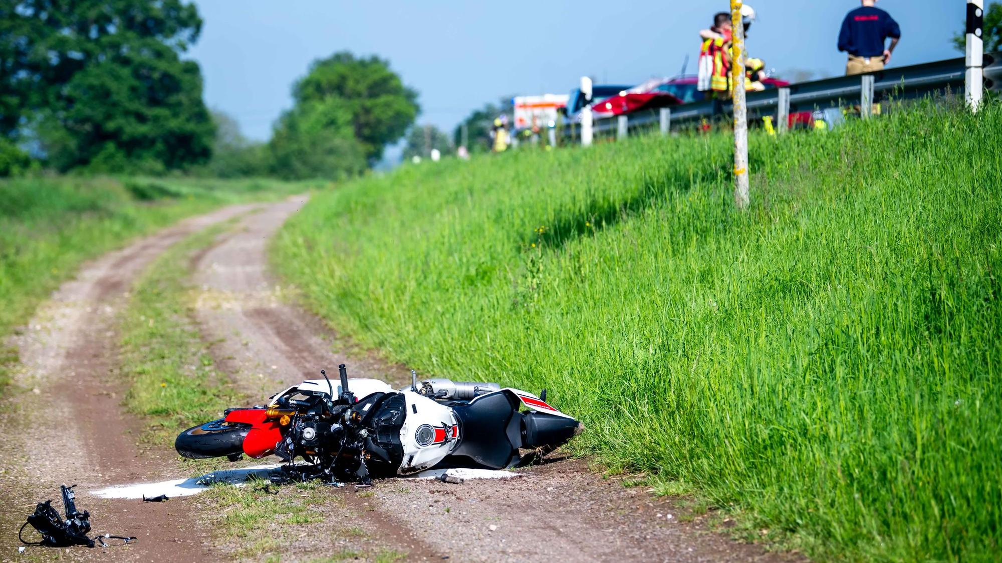 Ein Motorrad liegt nach einem schweren Unfall auf einem Feldweg. Rechts oberhalb ist die Landstraße bei Euskirchen zu sehen, wo sich der Unfall ereignete.