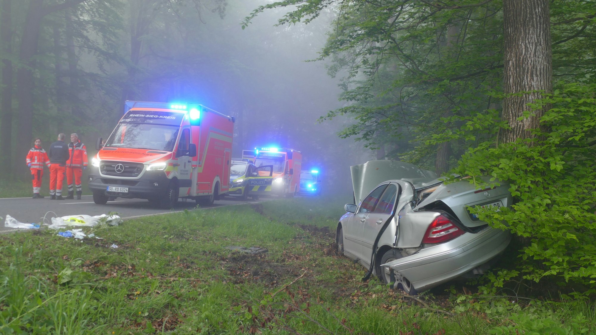 Ein Auto liegt im Graben, Rettungswagen stehen auf der Straße.