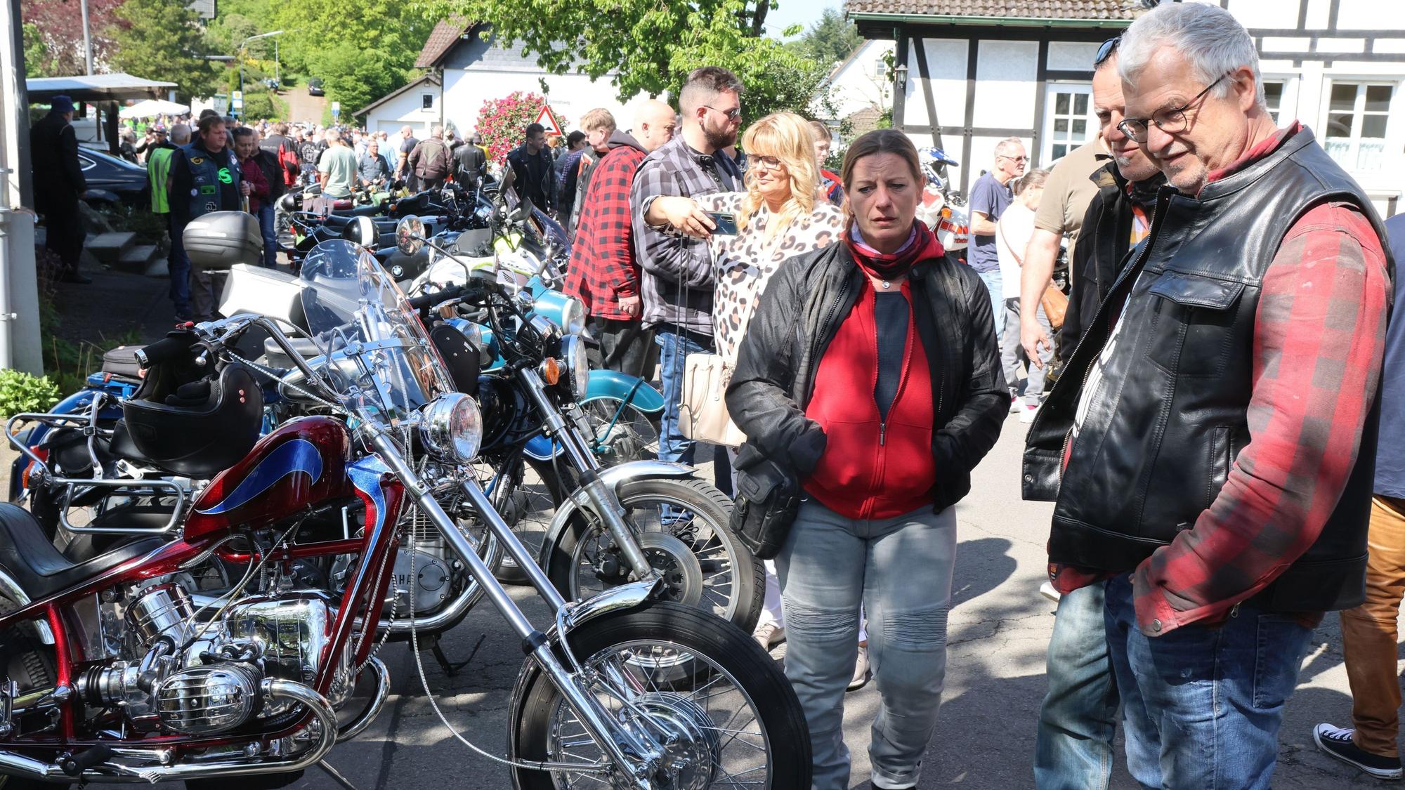 Viele Menschen stehen um eine Reihe von Motorrädern.