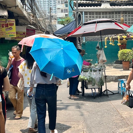 Thailand, Bangkok: Menschen schützen sich in Bangkok mit Schirmen vor der extremen Hitze und vor der Sonne.
