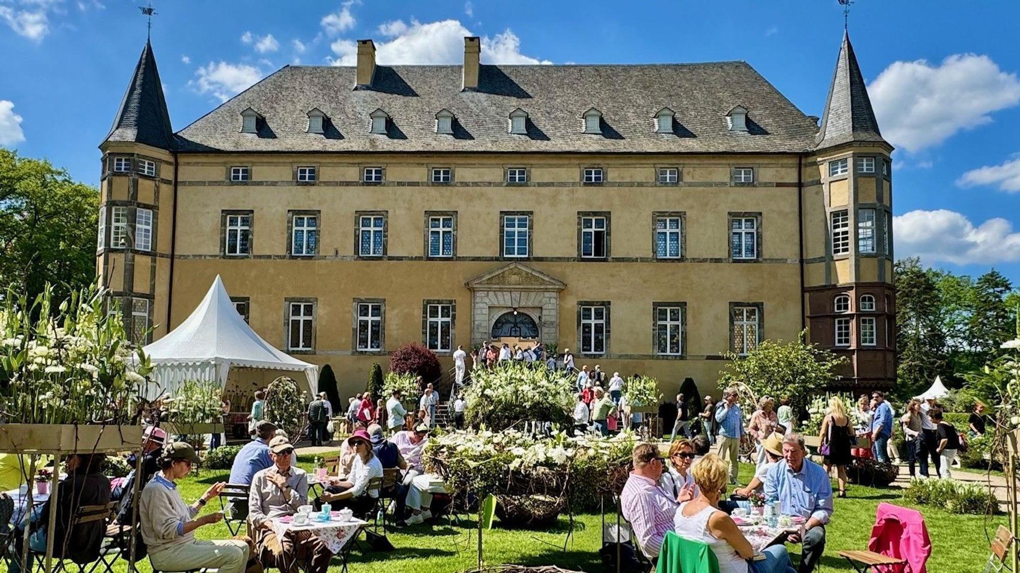 Wachtberg-Adendorf, Menschen sitzen an Tischen im schön dekorierten
Burggarten.