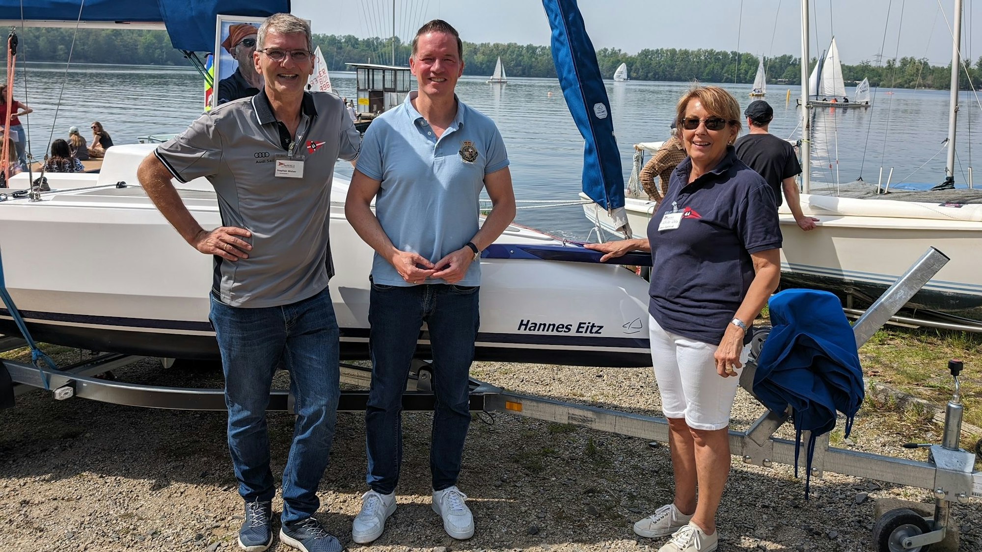 Drei Personen stehen vor einem Boot.